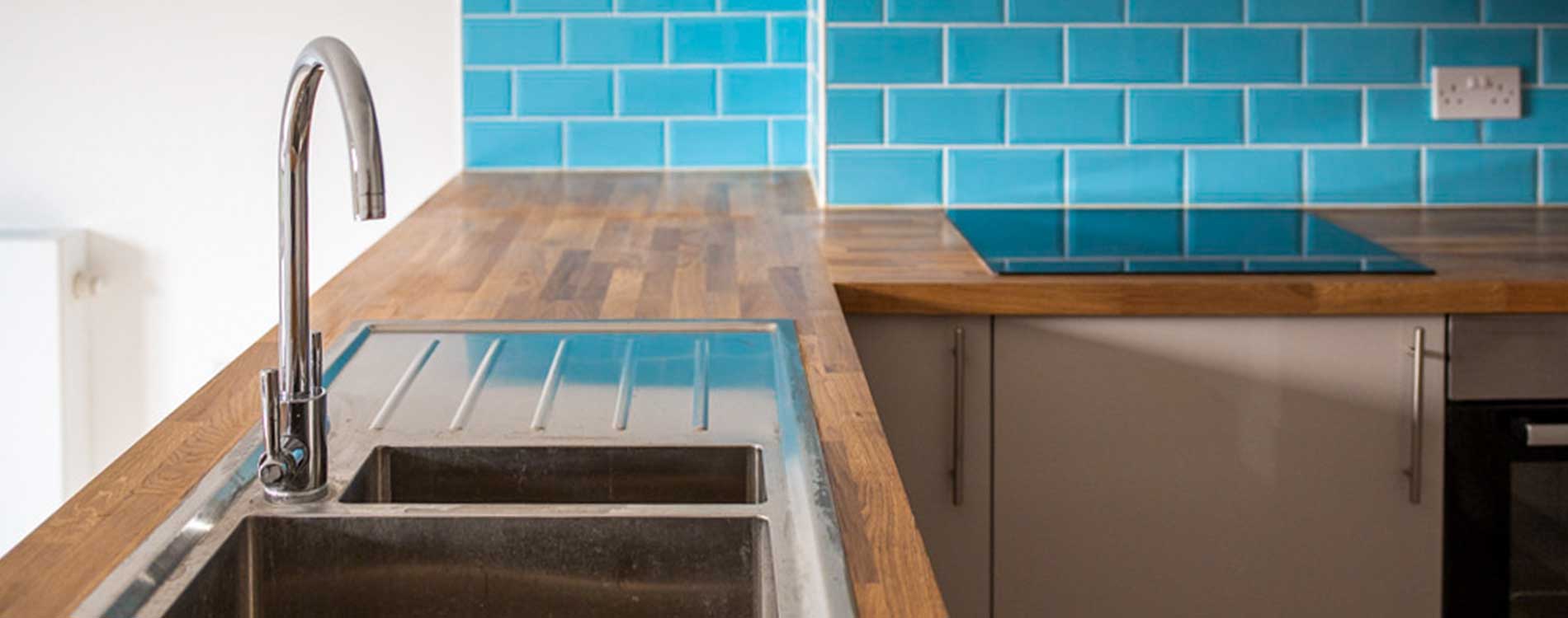 kitchen sink and blue tiled wall inside a brent housing conversion