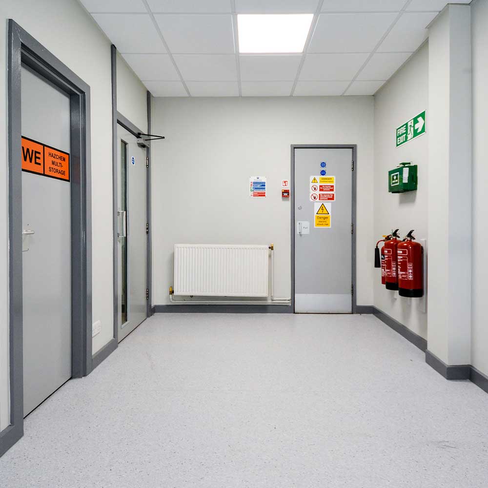 Fire extinguishers and warning messages inside a grey small room at romford police station