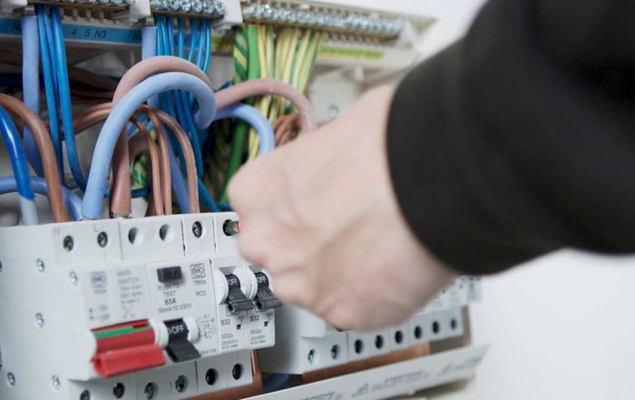 Electrician wiring a fuse board as part of axis Europe services