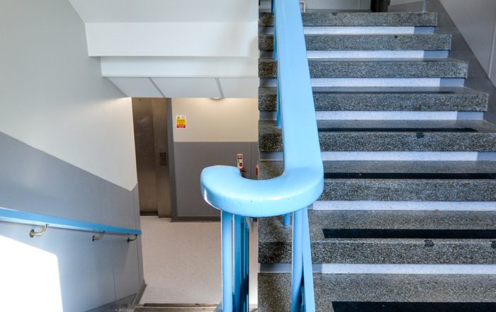 Staircase with a blue painted rail inside a police station refurbishment