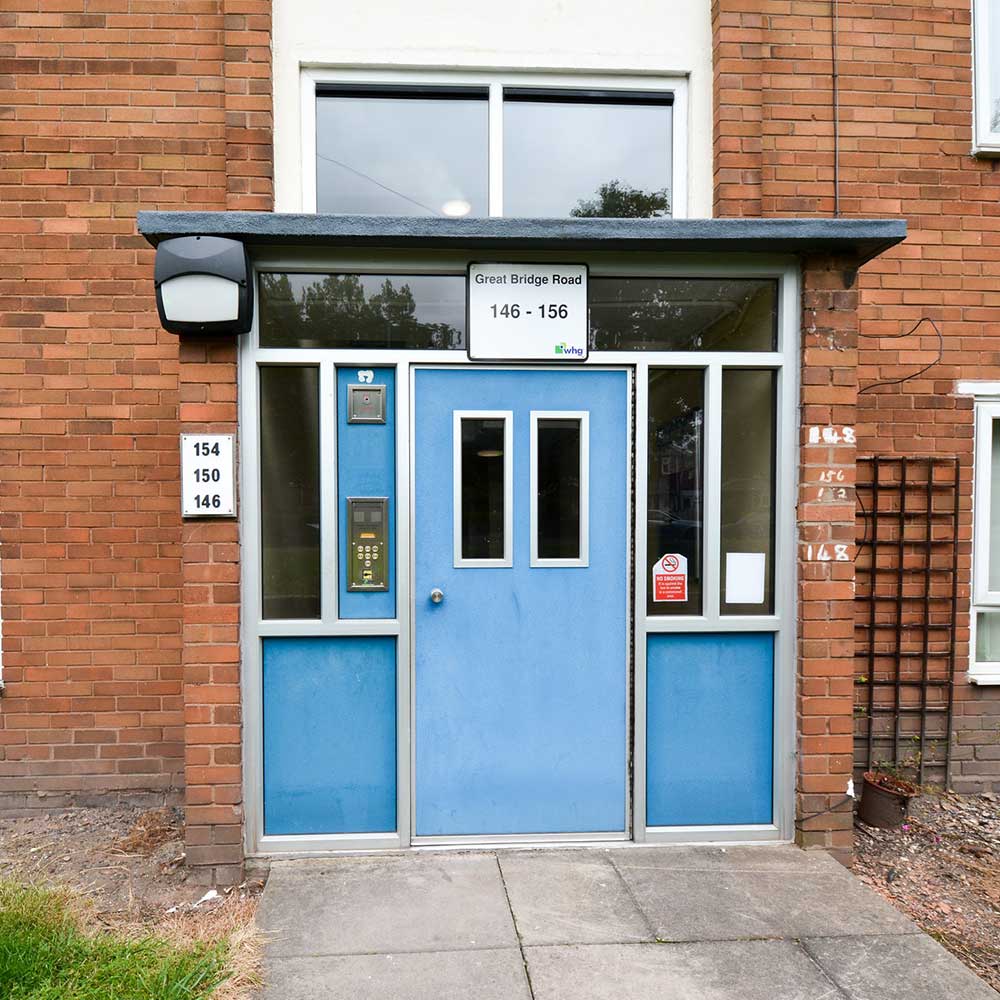 Entrance to a block of flats shows a blue door and the name great bridge road