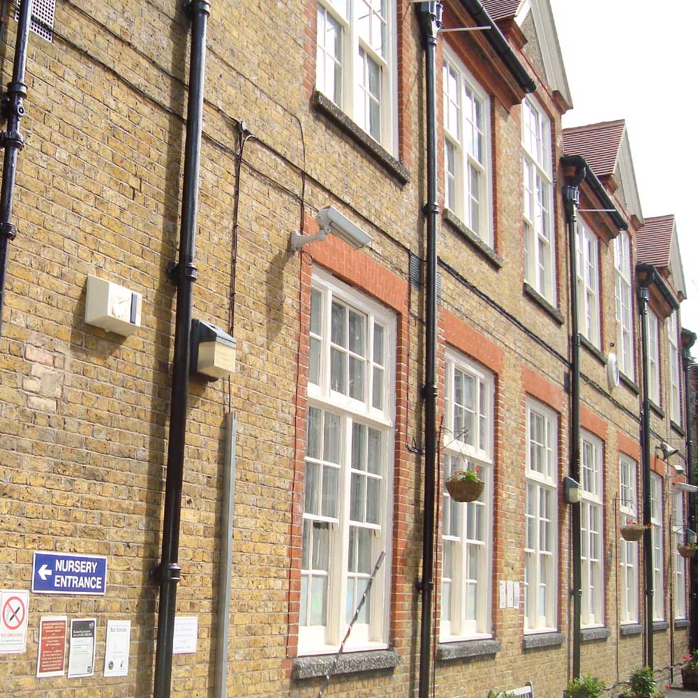 Renovated windows, brickwork and pipes along the side of an school