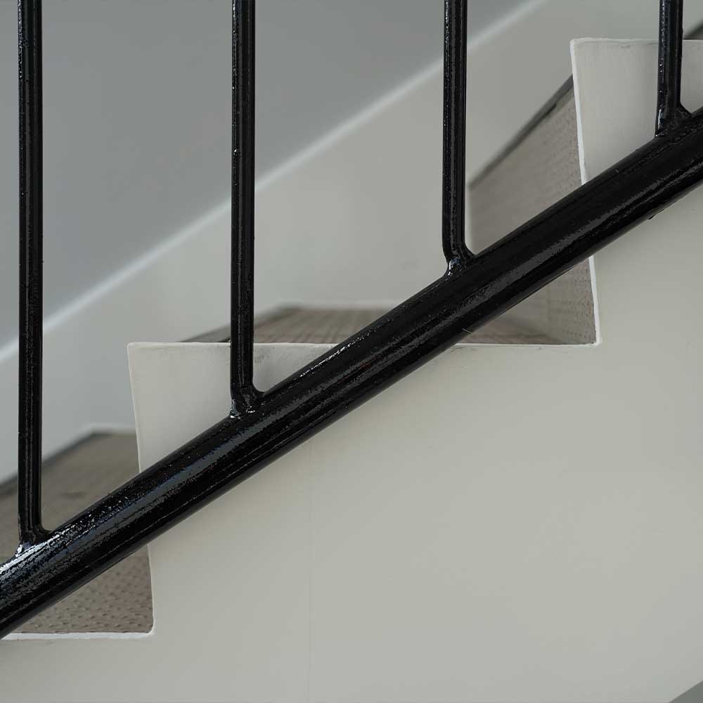 Side view of white and grey staircase with fresh painted black railings