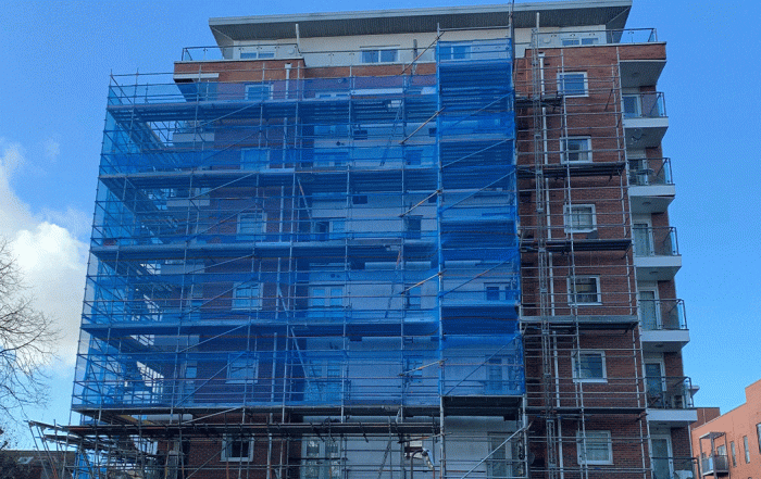 Building covered in blue netting and scaffolding replacement cladding project