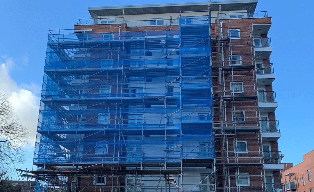 Building covered in blue netting and scaffolding replacement cladding project
