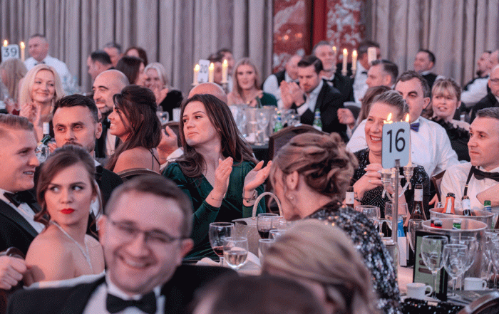 large number of people at dining tables laughing and enjoying charity ball
