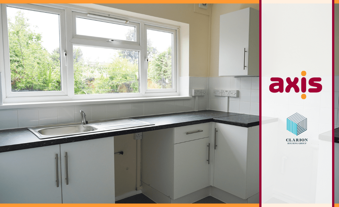 White kitchen with cupboards, sink, and window with garden. Axis logo on the right and Clarion logo on a white banner with red borders.