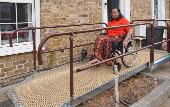 Lady in a wheelchair on a ramp. Ramp is from the door to the pavement