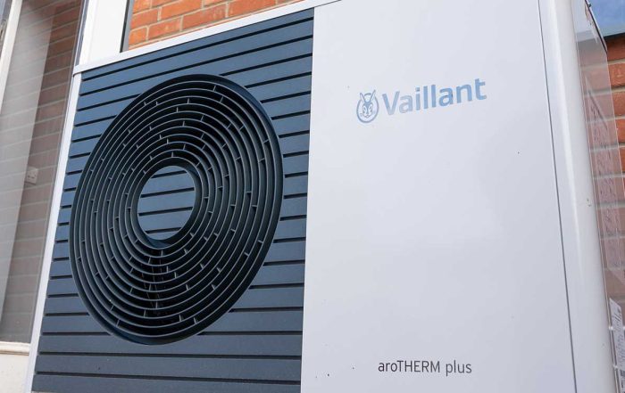 Vaillant installation outside with a door on the left and brick wall behind.