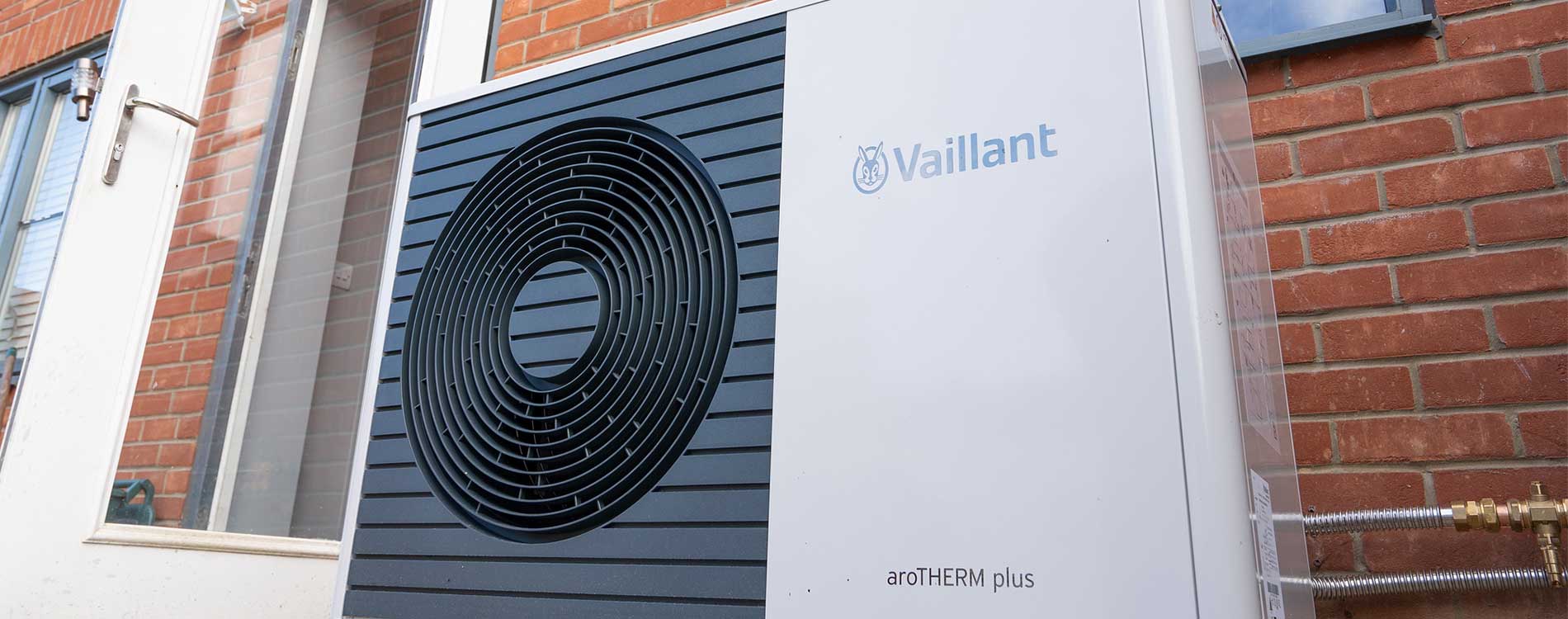 Vaillant installation outside with a door on the left and brick wall behind.