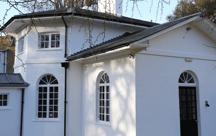 Old white house with black roofs, windows and doors.