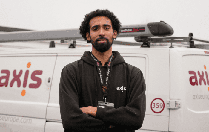 Man with black hoodie, standing in front of a white Axis Europe van.