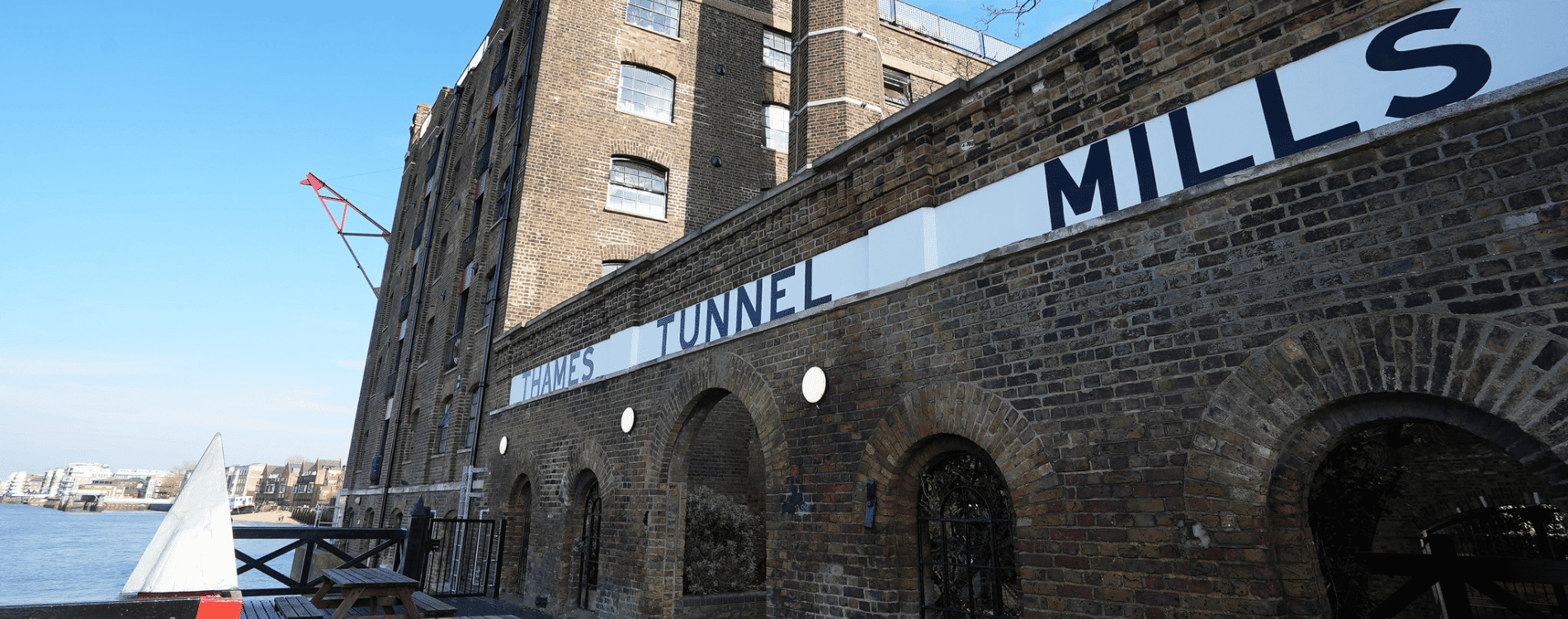 Thames Tunnel Mills sign along side elevation of brick building with arches