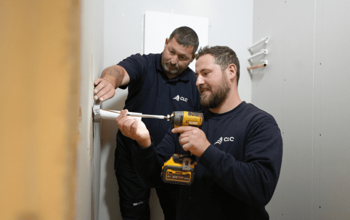 Two operatives installing a fire door