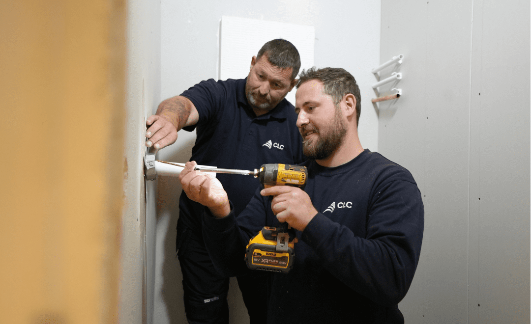 Two operatives installing a fire door
