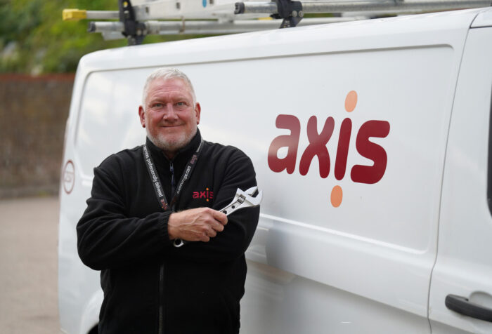 Axis operative holding spanner in front of white van.