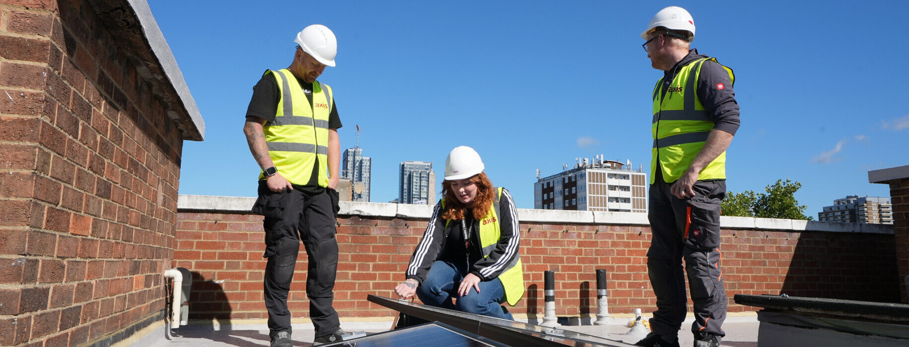 three operatives installing solar panels on a roof