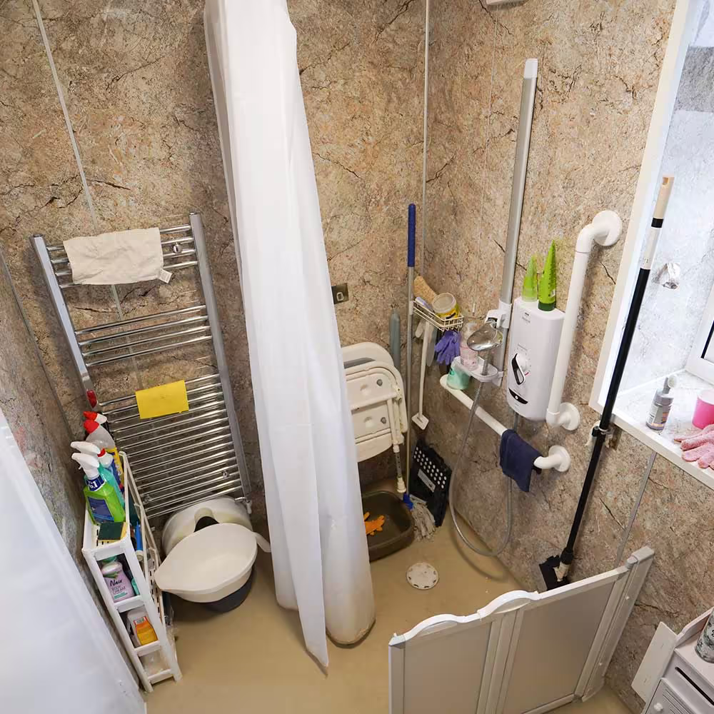 The interior of a newly fitted accessible wet room, showing the level-access shower area and strategically placed grab rails for safety.