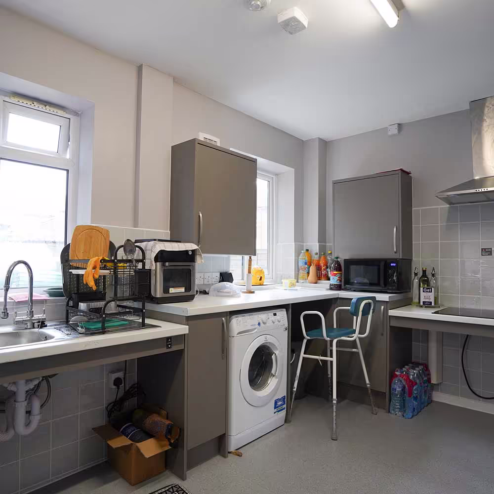 A wide view of a fully adapted kitchen, featuring lowered worktops and clear space under the hob and sink to accommodate a wheelchair user.
