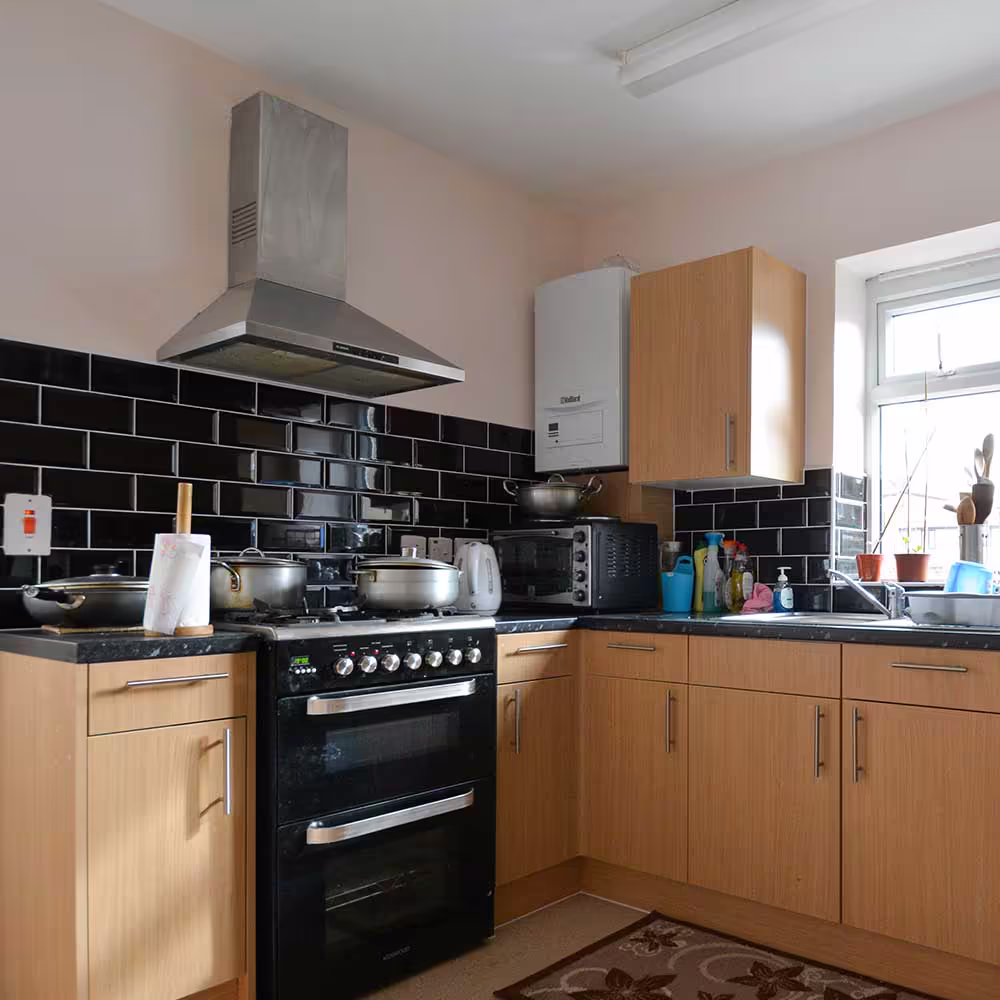 The original kitchen before the extension, featuring oak-effect cabinets, a black tiled backsplash, and a freestanding cooker.