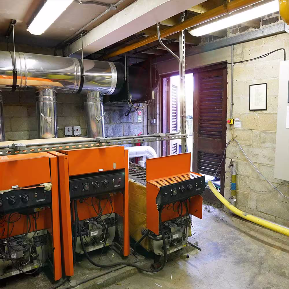 The old and inefficient communal boilers in the plant room during the decommissioning process, prior to being replaced with a modern system.
