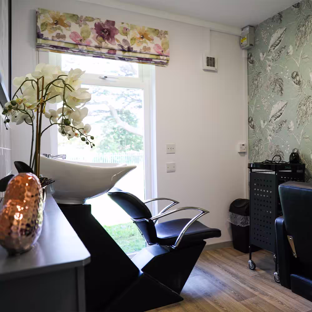 The new on-site hairdressing salon installed during the communal refurbishment, showing a professional salon chair and backwash basin in a stylish room.