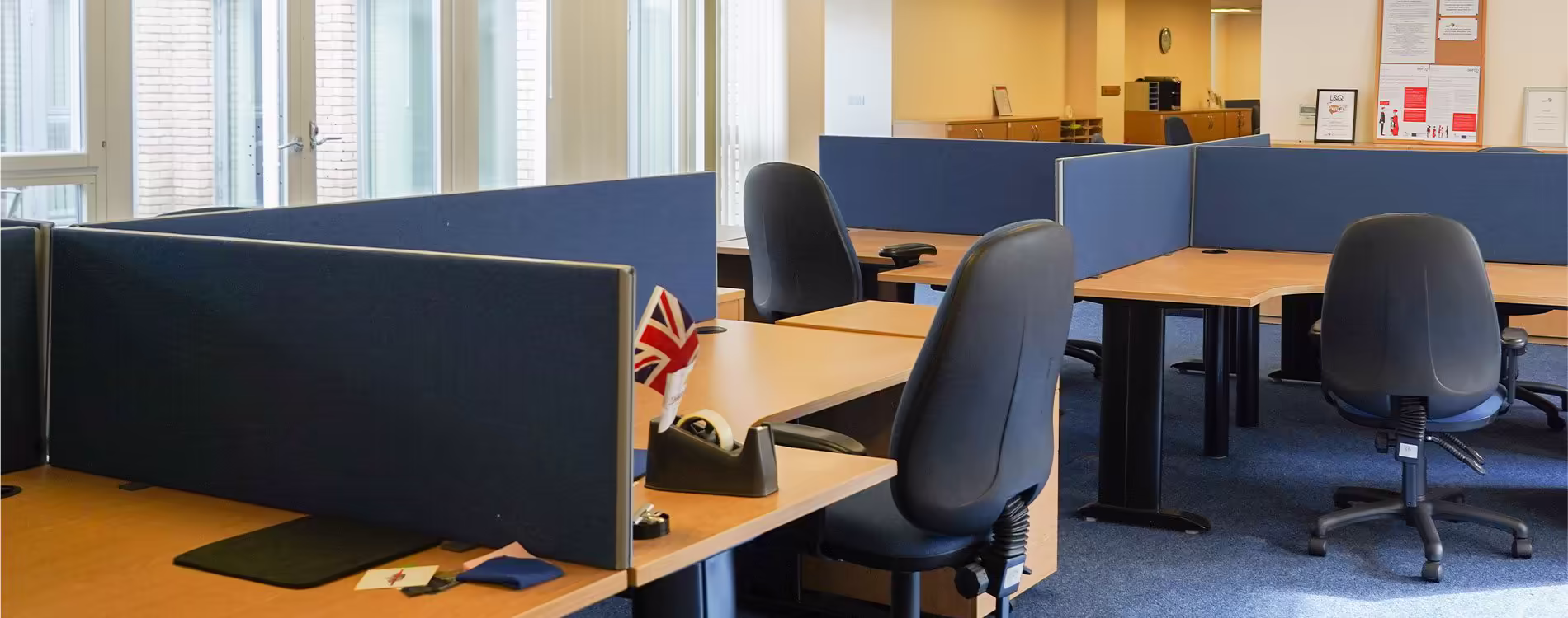 The newly refurbished office space in a community centre, featuring modern desks with blue privacy dividers and ergonomic chairs.