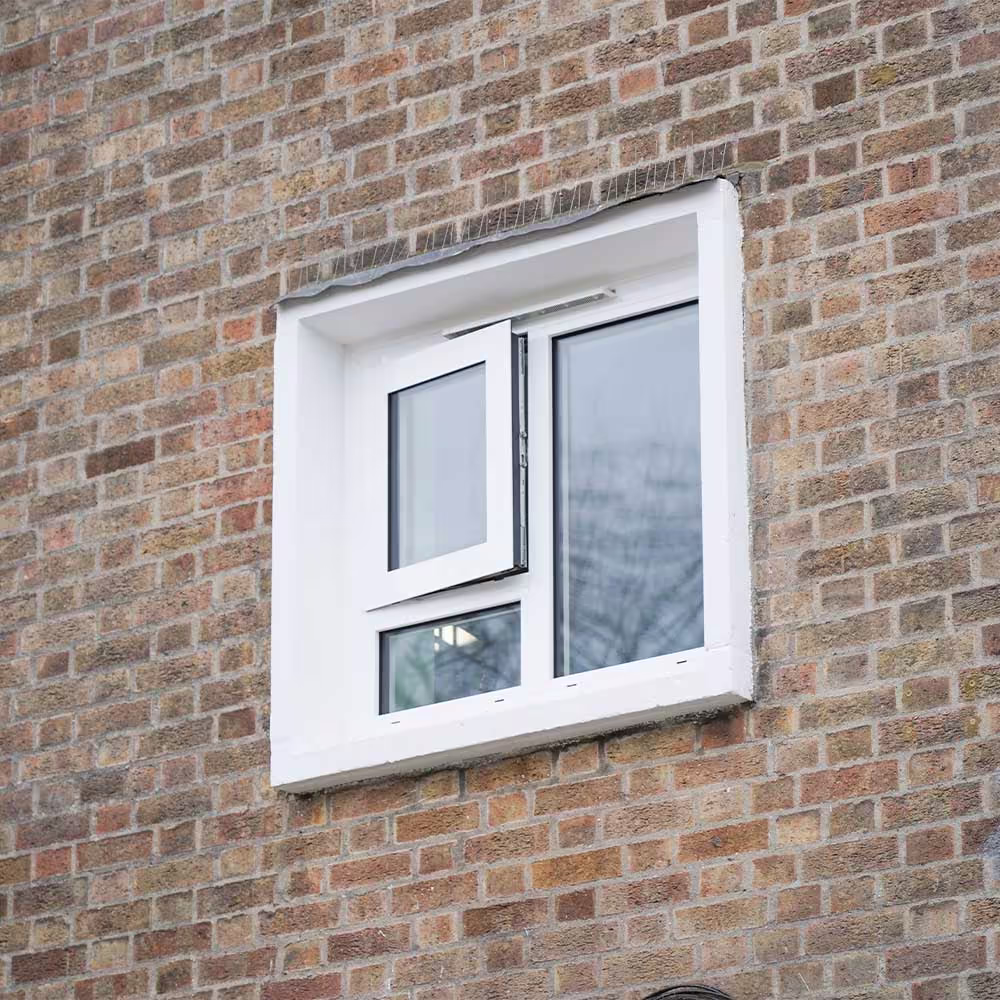A new, white-framed window with an openable top casement, neatly installed into a brick wall as part of a cyclical window repair and replacement programme.