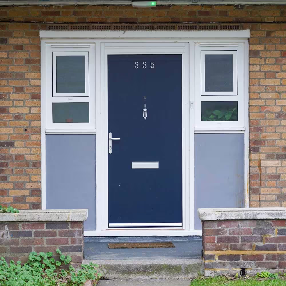 The front entrance of a property after re-decoration, showing a newly painted dark blue front door and freshly painted white and grey surrounding panels.