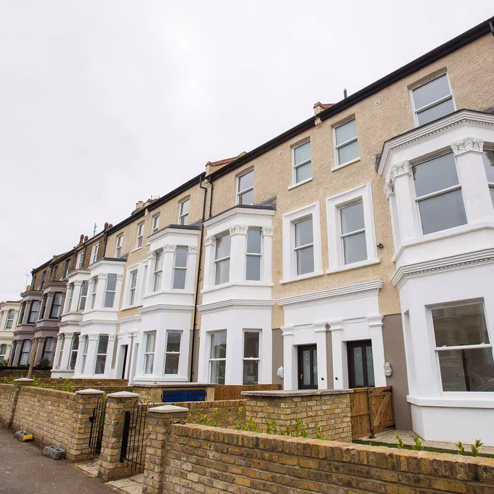 A street-level view of a row of converted terraced houses, showcasing the extensive scope of the derelict property renovation project and the uniform, high-quality finish.