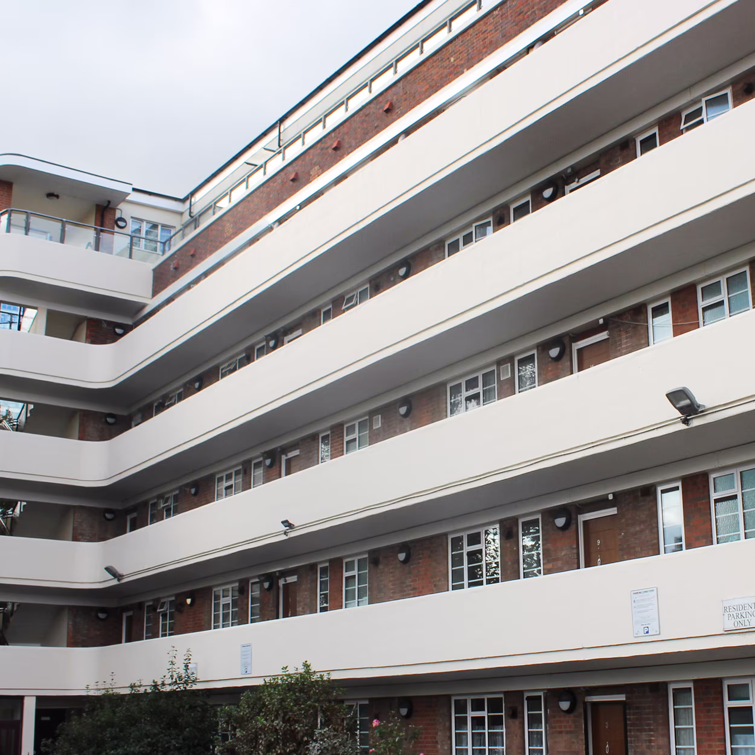 Wide shot of a multi-storey Art Deco apartment building after an exterior redecoration project, highlighting its distinctive curved white balconies.