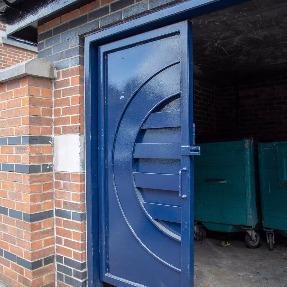 A close-up of a newly painted blue metal door on a communal bin store, showcasing the high-quality finish of external maintenance redecorations.
