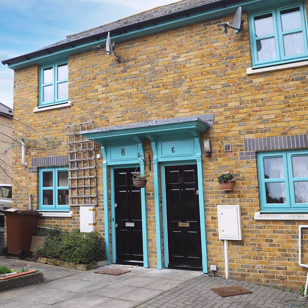Two front entrances of a property, showing newly painted black doors with vibrant turquoise surrounds and canopies, an example of detailed external property decoration.