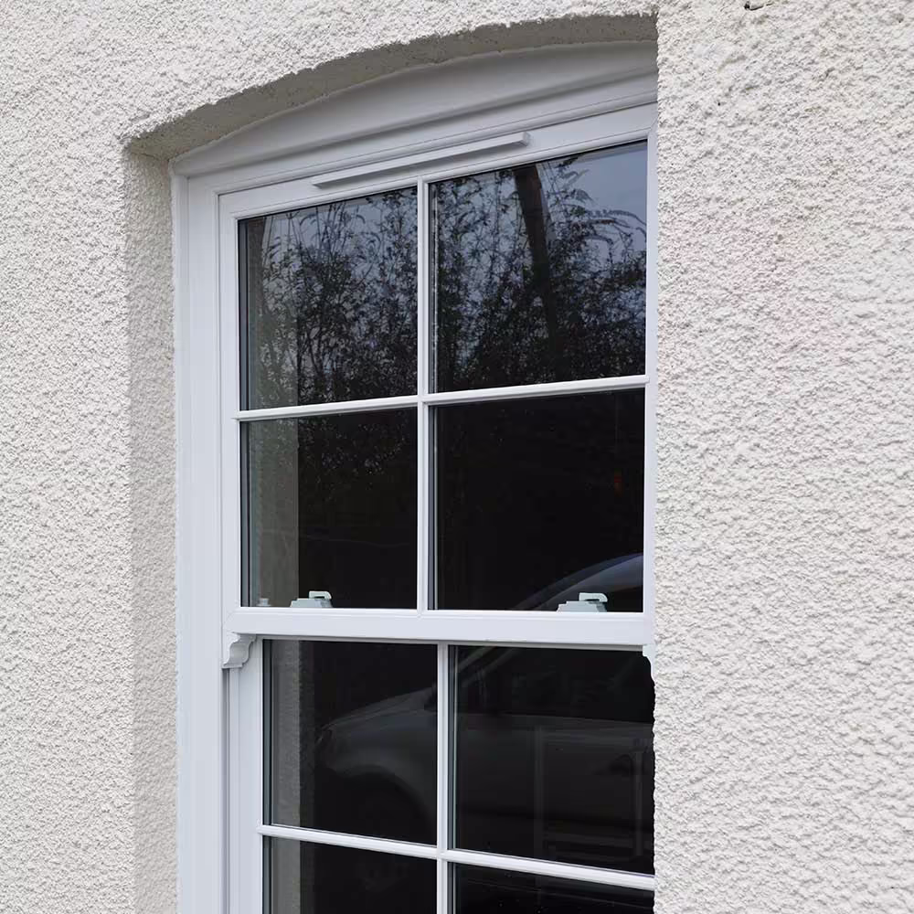 A close-up of a new, white uPVC sash window installed in a textured rendered wall, demonstrating a high-quality window replacement as part of external property services.