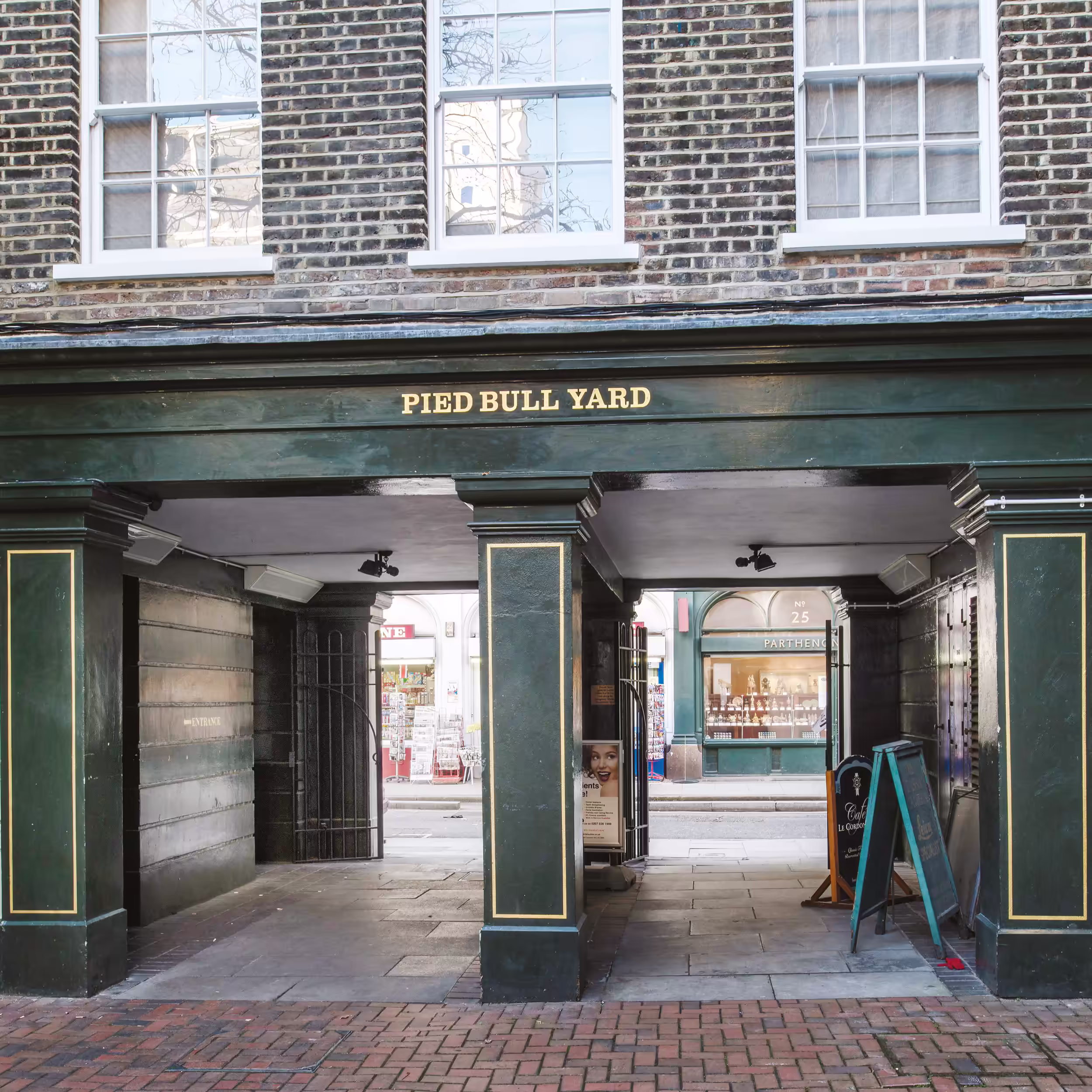 The immaculately redecorated dark green entrance archway to 'Pied Bull Yard', with gold lettering, leading from a main street.