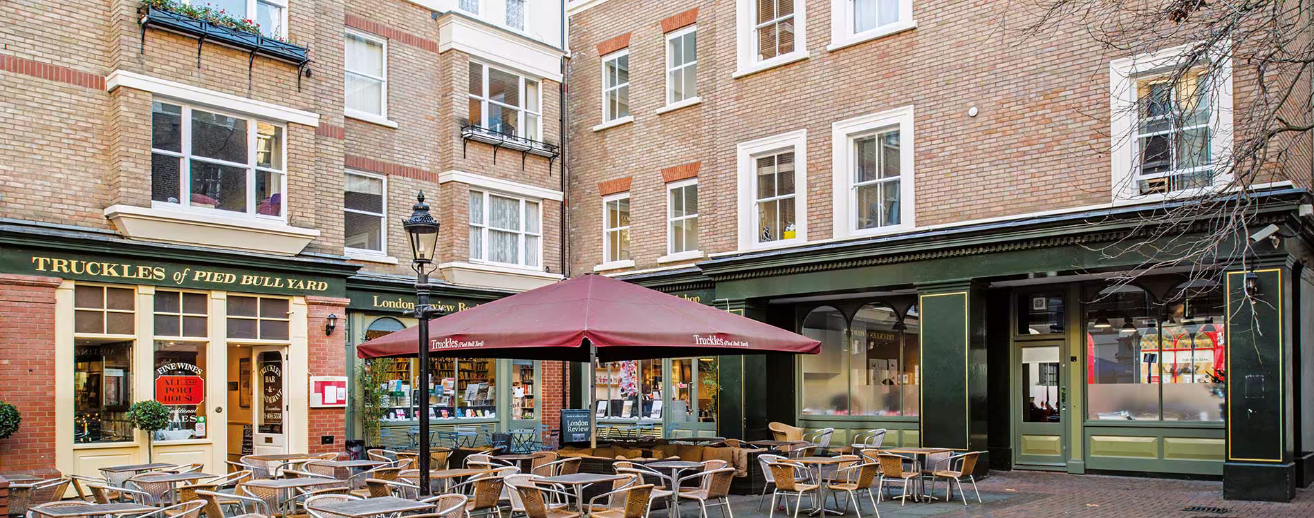 Panoramic view of the charming 'Truckles of Pied Bull Yard' restaurant courtyard after external redecorations, showing the well-maintained brick buildings and outdoor seating.