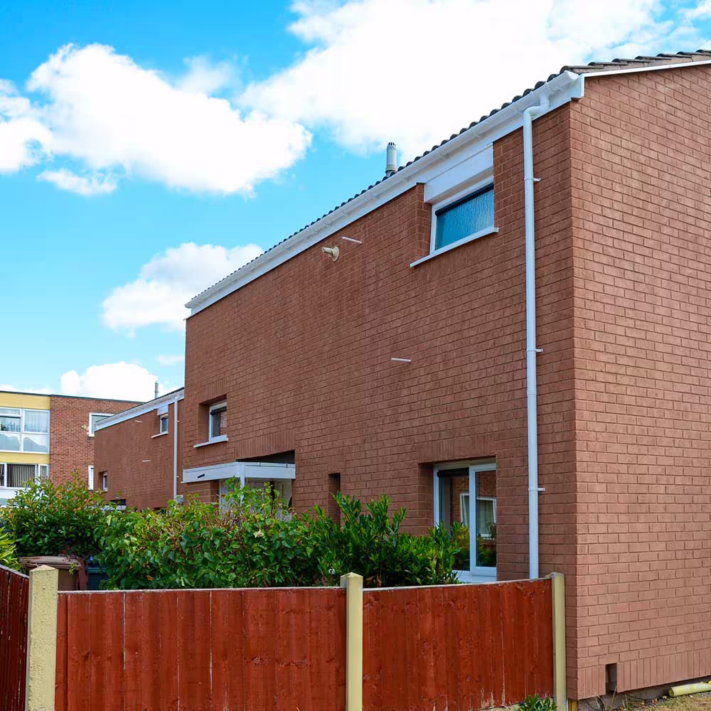 Rear garden view of a Lowrey Close property with smooth rendered walls and updated fencing following the EWI programme.