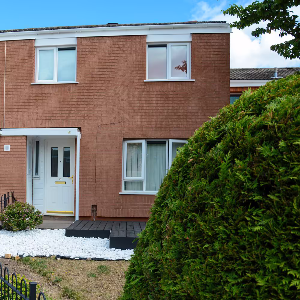 Side garden and patio area beside a terraced home wrapped in new external insulation and light-toned render.