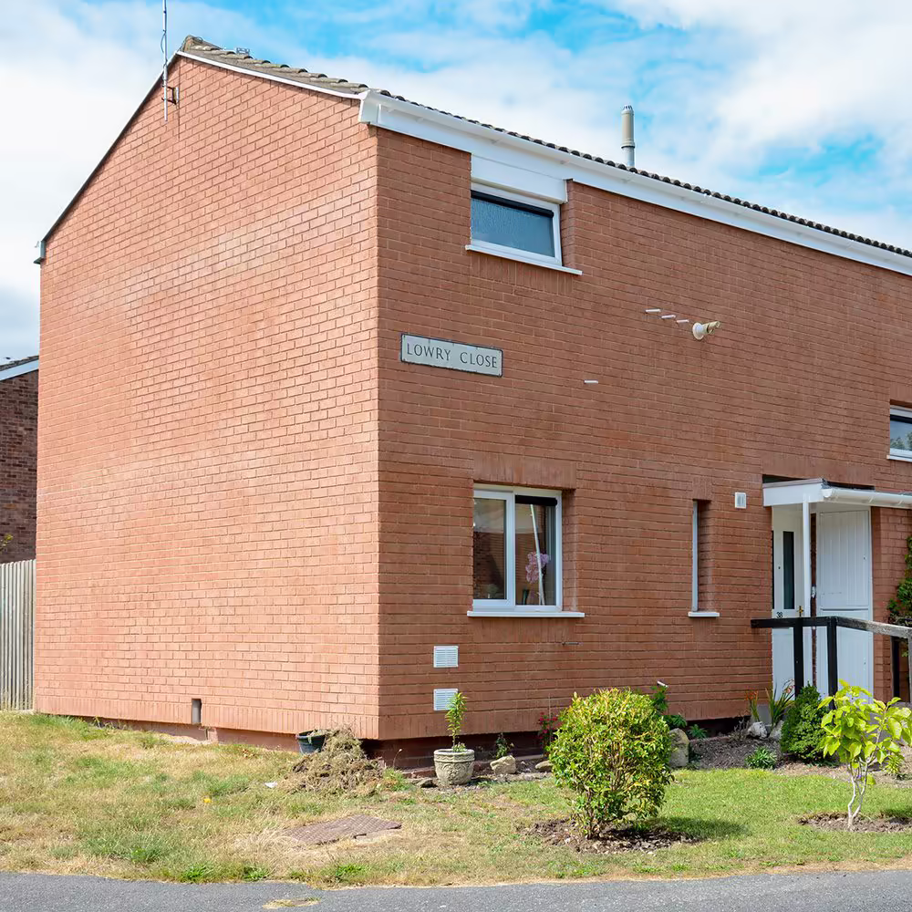 Side elevation of a Lowrey Close property showing insulated walls, refreshed window reveals, and neatly edged lawn.