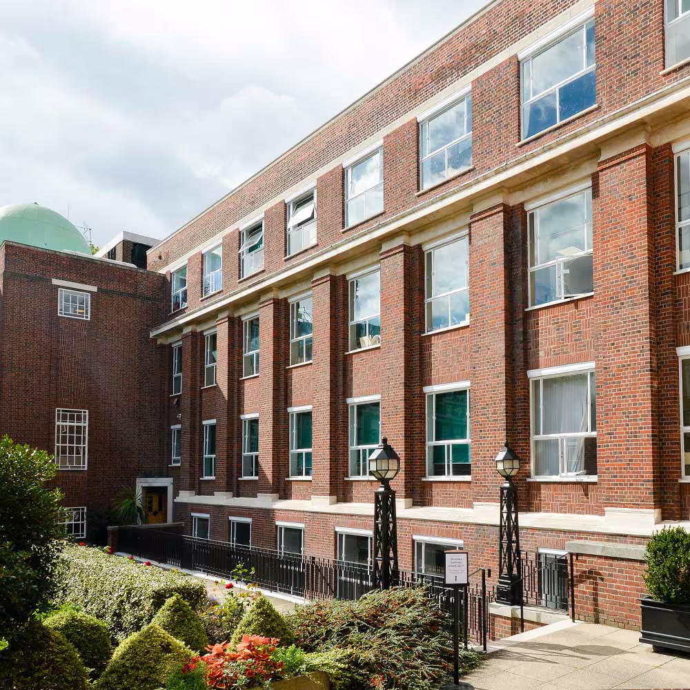 Ground-level view of the refurbished Regent's University entrance showcasing repointed brickwork and cleaned stone detailing.