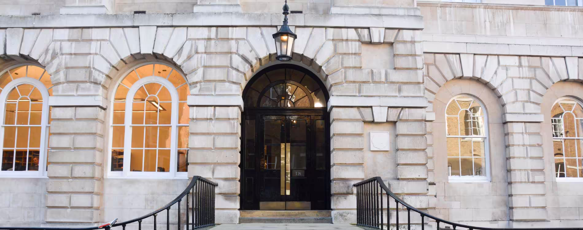 The grand, symmetrical stone facade of a Grade Listed building after repairs, showing the impressive arched entrance and windows.