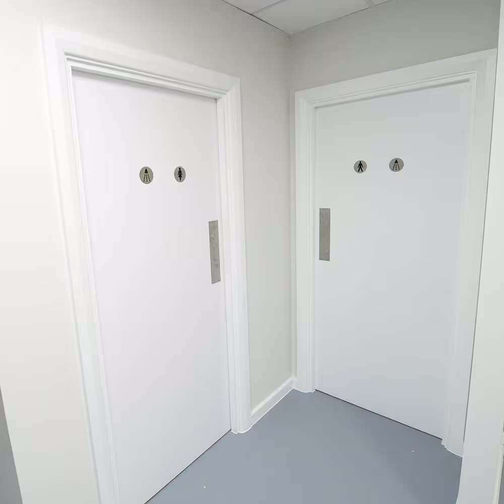Renovated gymnasium changing facilities, showing two new white doors with male and female shower pictograms.