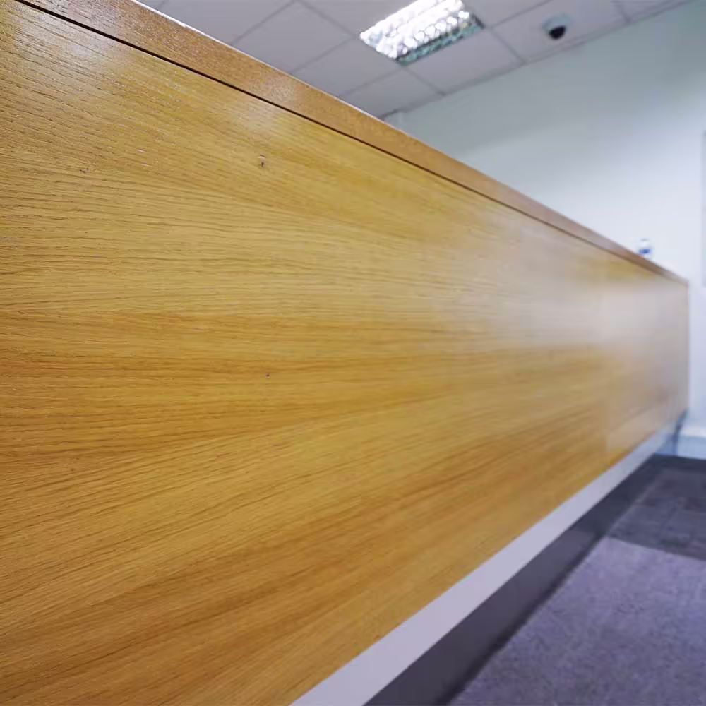 A close-up of the high-quality, light oak finish on the bespoke reception desk, a key feature of the modernised heritage building interior.