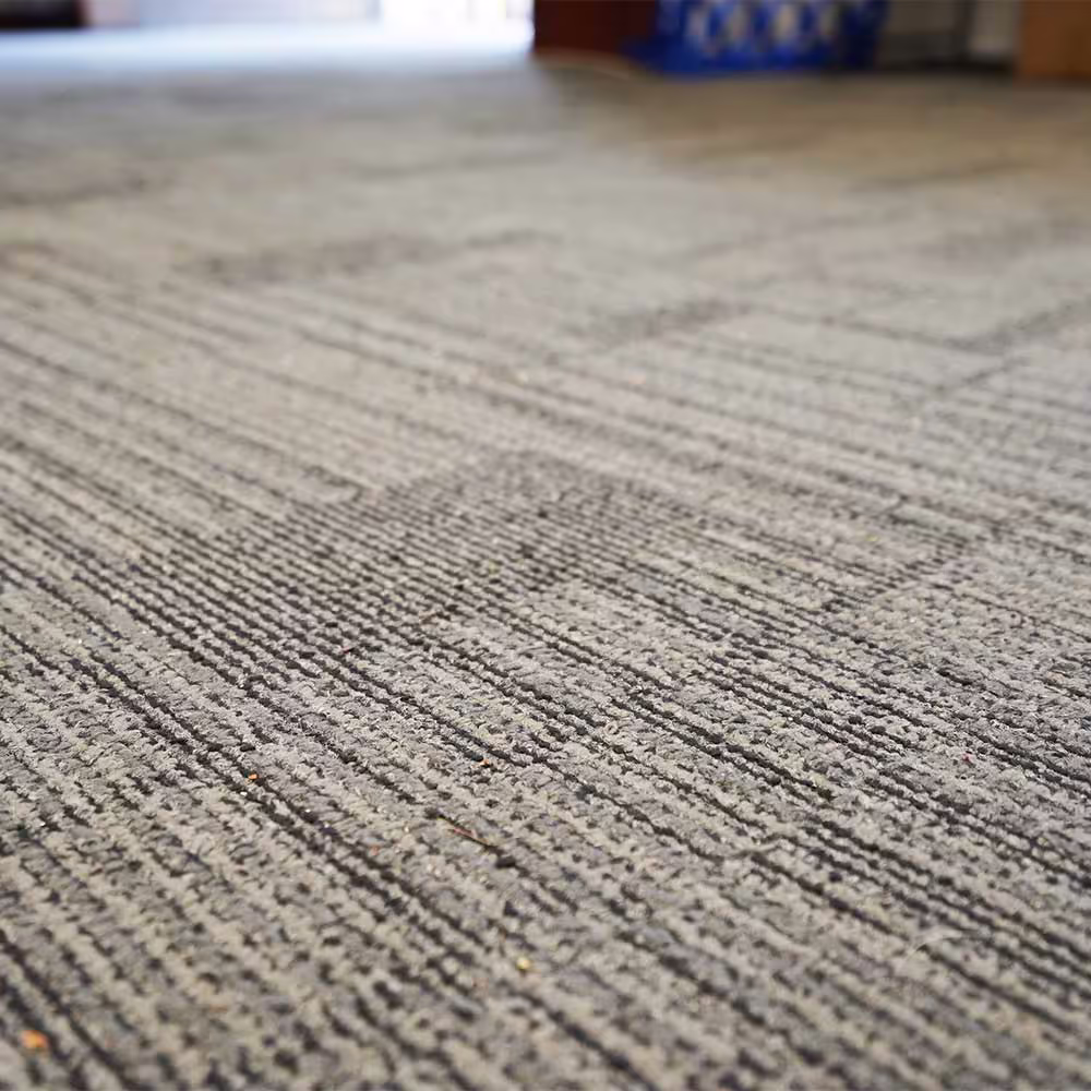 A low-angle, close-up view of the new, hard-wearing grey carpet tiles installed throughout the refurbished office space in the heritage building.