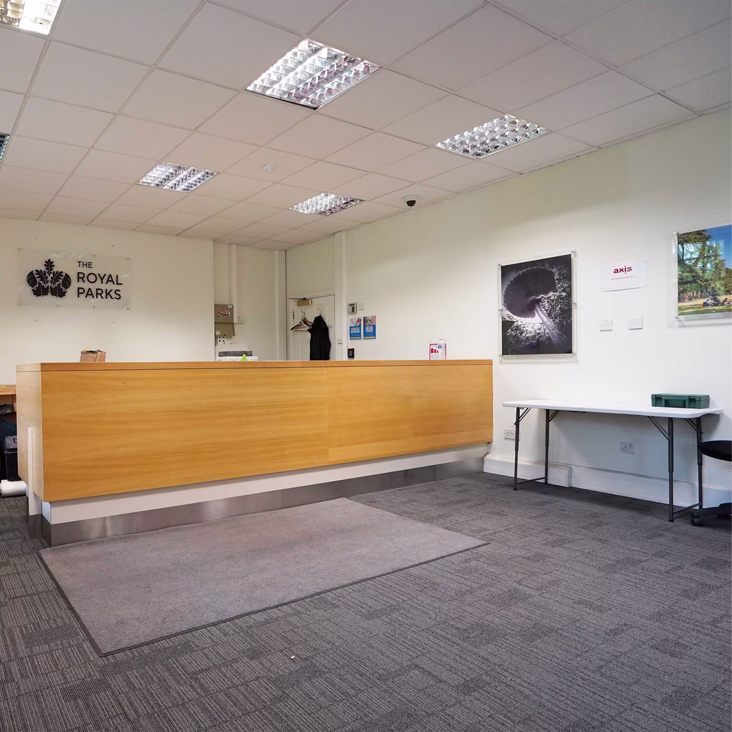 The newly refurbished and modernised reception area for The Royal Parks, featuring a long wooden desk, new grey carpet tiles, and clean white walls.