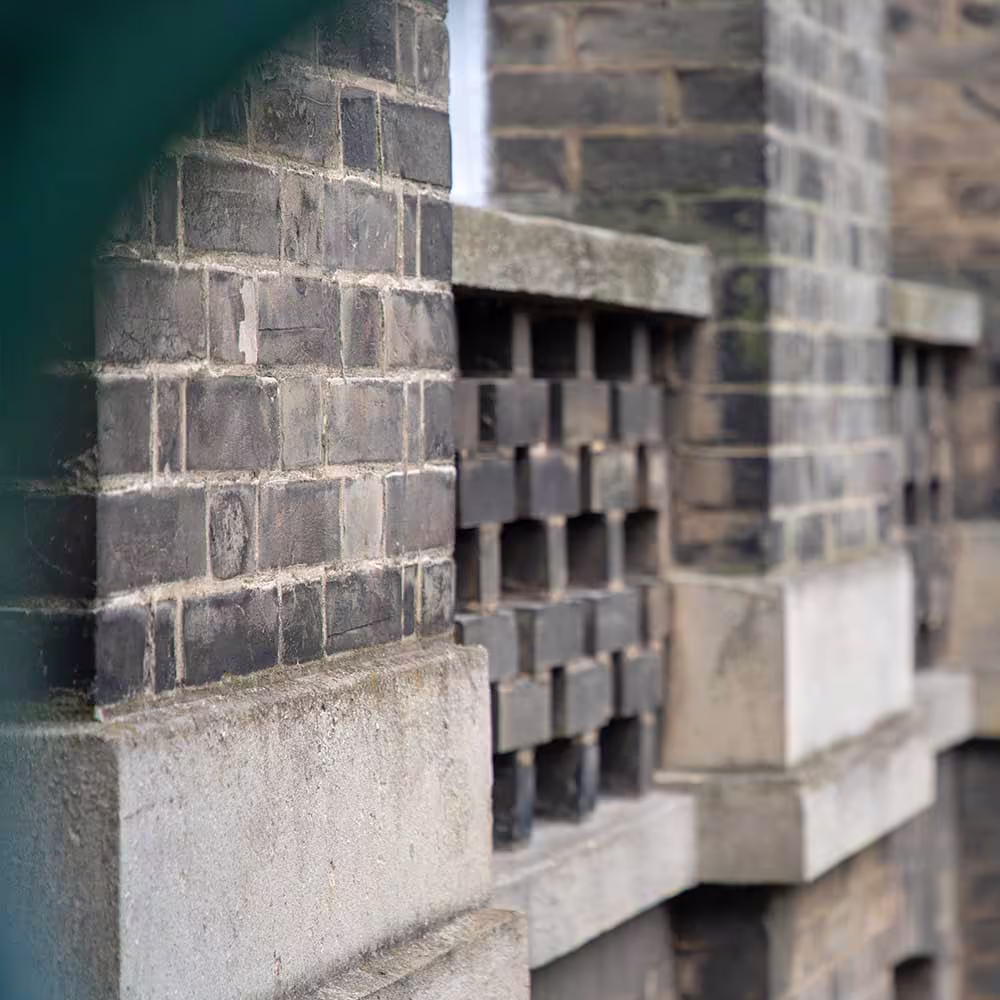 A detailed architectural shot of decorative pierced brickwork on a historic building, a feature that has been carefully preserved during the repair process.