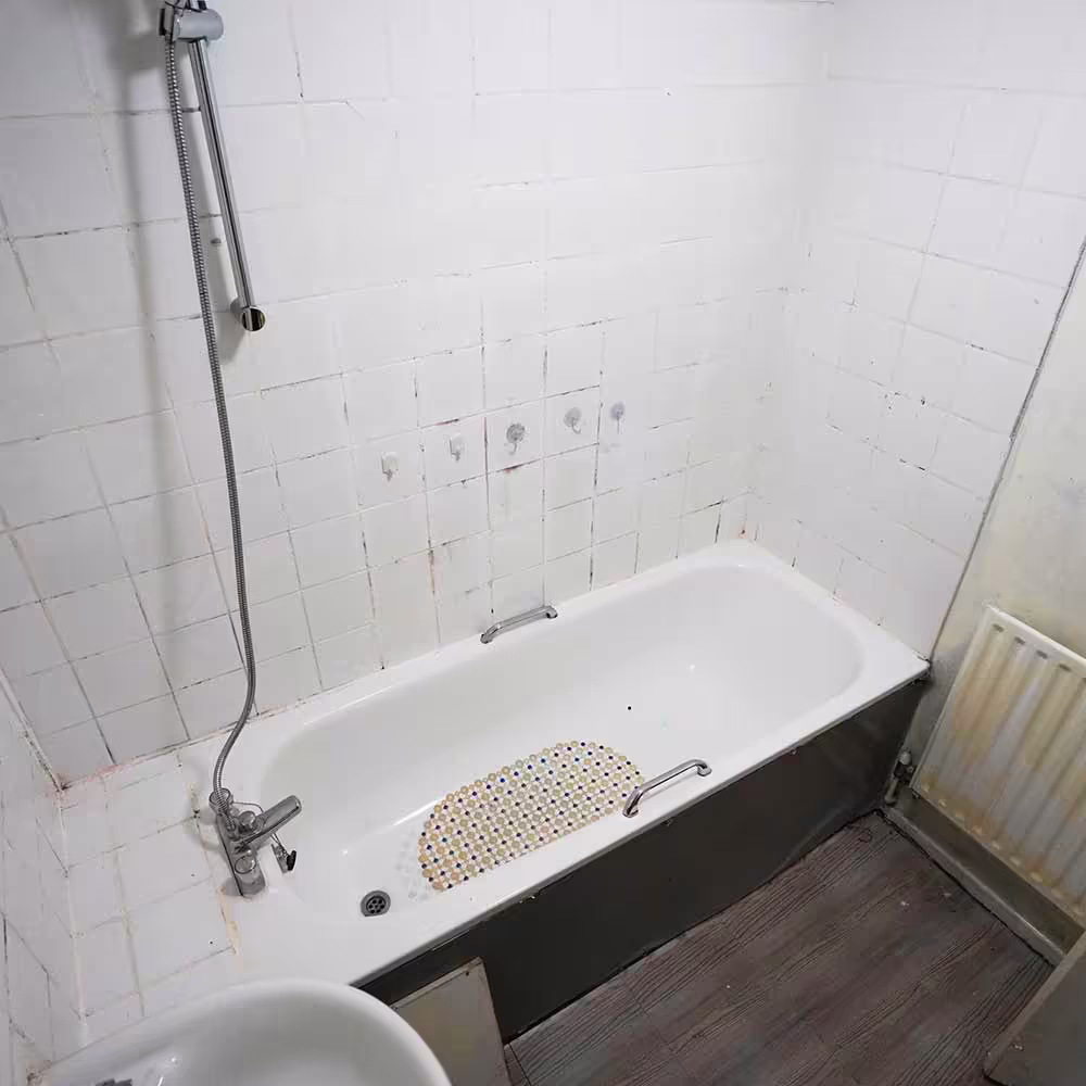 The old bath and damaged wall tiles in a Westminster City Council property, showing the condition before the bathroom replacement programme.