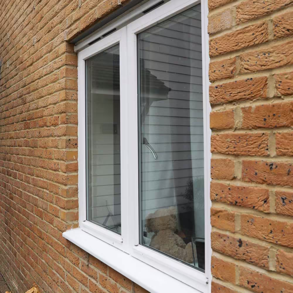 A close-up of a well-maintained white uPVC window set into a brick wall, an example of a minor external repair on a residential property.