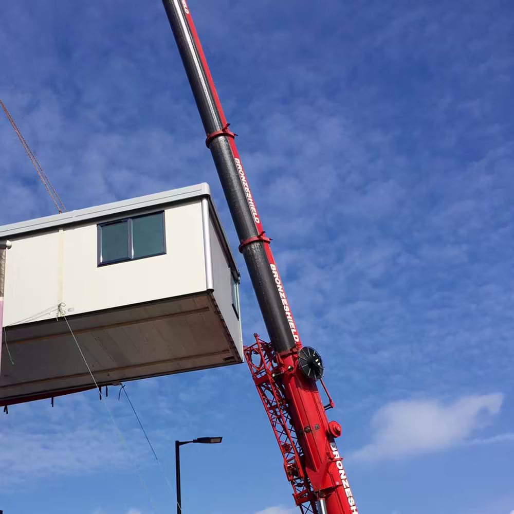 Close-up of modular building section being secured onto steel supports during assembly.