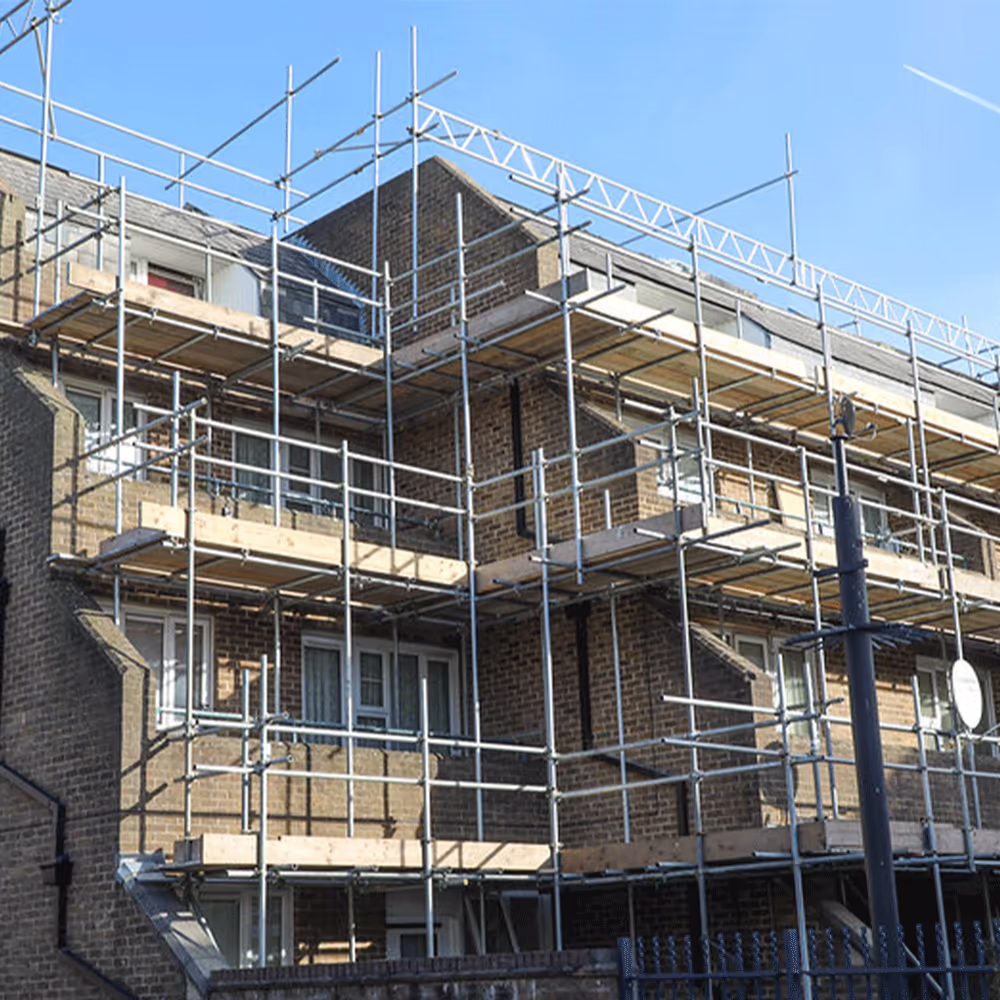 Construction manager on site overseeing simultaneous works across different building phases.